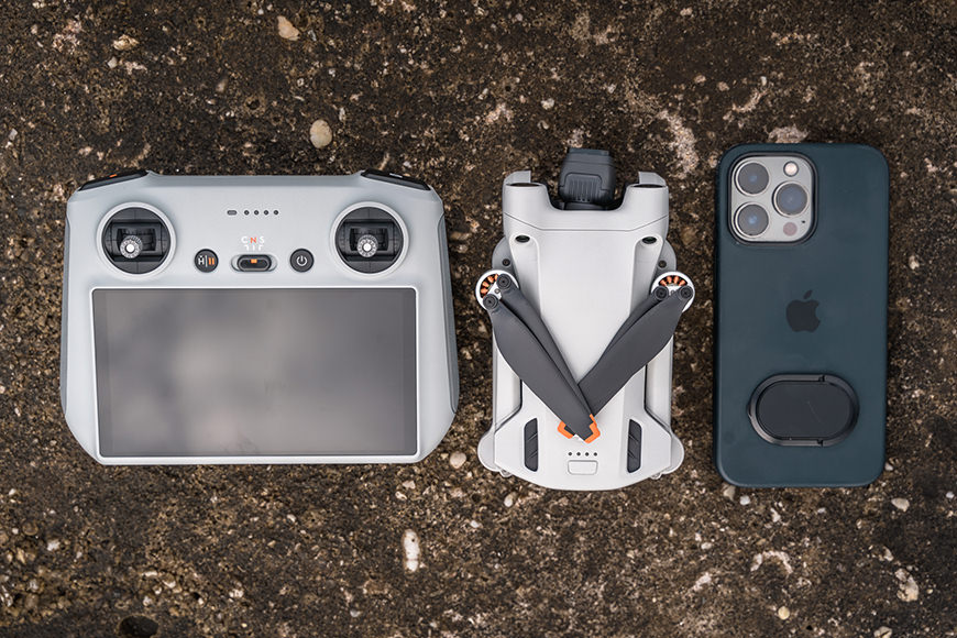 The DJI Mini 3 Pro as compared to the controller and an iPhone 13 Pro.